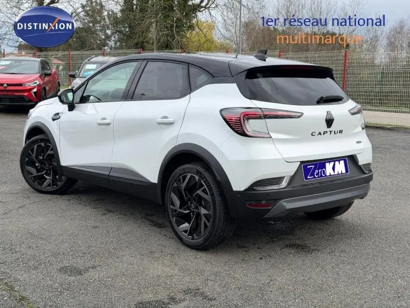 Vue 3/4 arrière droite du Renault Captur blanc nacré avec toit noir et jantes noires distinctives.