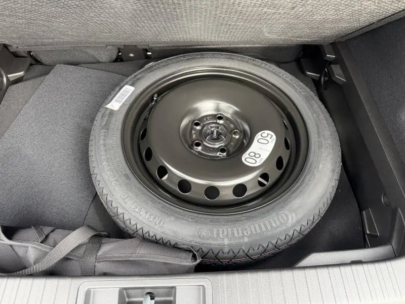 Vue plongeante sur la roue de secours noire dans le coffre du Renault Captur blanc nacré 2026 esprit Alpine.