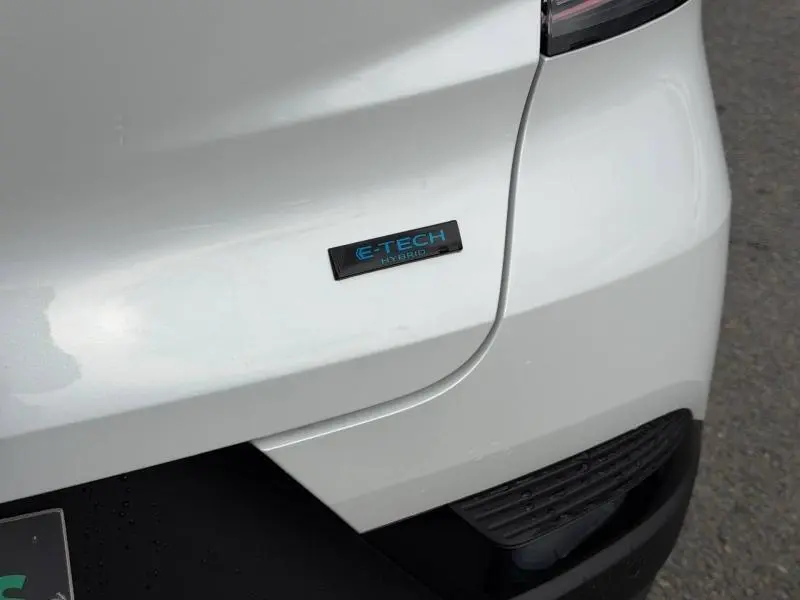 Gros plan sur l'arrière droit blanc nacré du Renault Captur 1.8 E-Tech avec logo E-Tech Hybrid bleu.