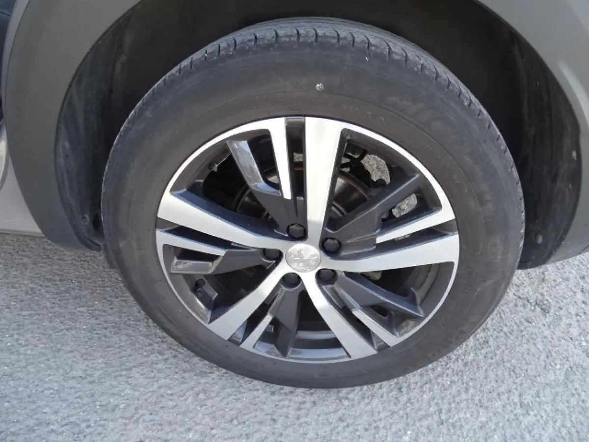 Gros plan sur la roue avant droite du Peugeot 3008 gris Artense, jante alliage bicolore au design moderne.