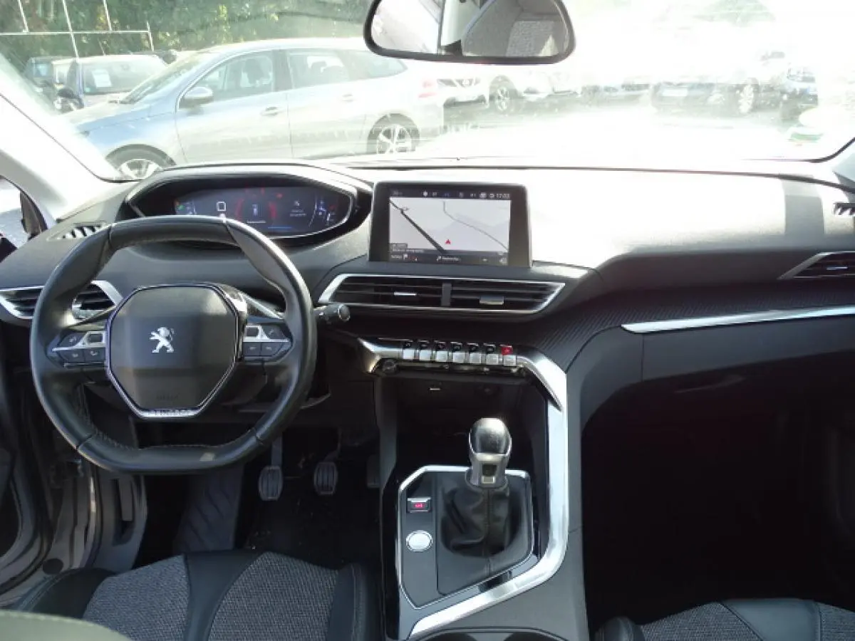 Vue intérieure frontale du Peugeot 3008 gris Artense 2017, avec tableau de bord numérique et console centrale équipée de touches piano chromées.