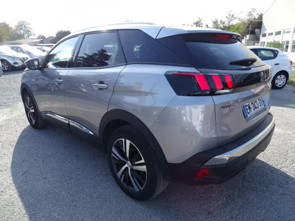 Peugeot 3008 gris Artense en 3/4 arrière droit, avec barres de toit aluminium et feux arrière à griffes rouges.