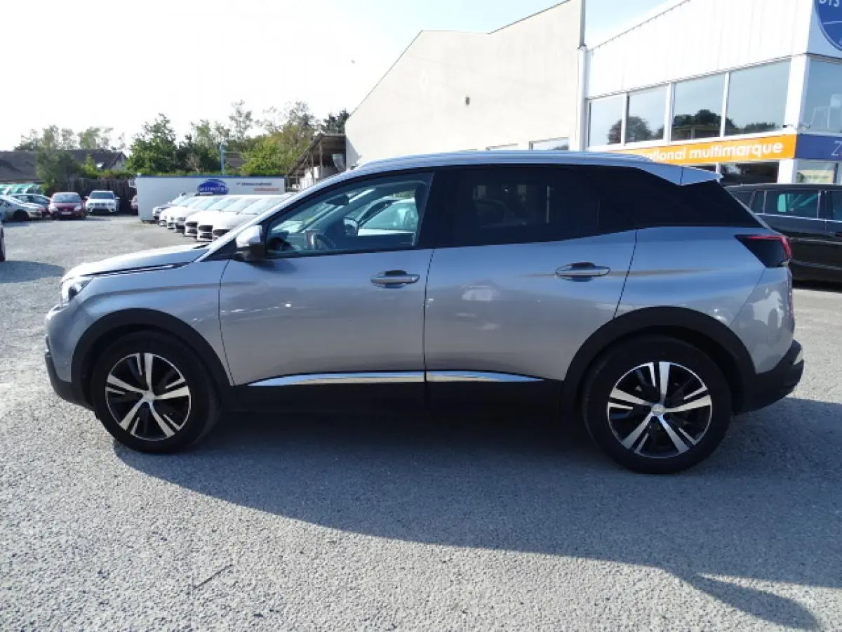 Profil droit du Peugeot 3008 gris Artense avec toit noir et barres de toit en aluminium visibles sur parking.