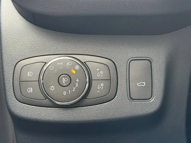 Gros plan sur la commande d’éclairage noire du Ford Puma 2024, avec bouton de réglage des phares et ouverture du coffre.