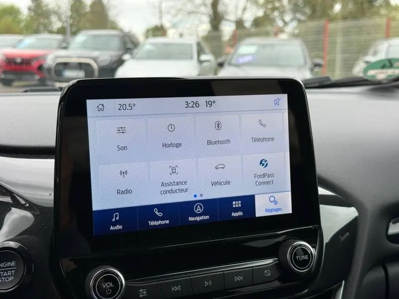 Vue intérieure centrée sur l'écran tactile du Ford Puma 2024, affichant le menu des réglages avec commandes audio et connectivité.