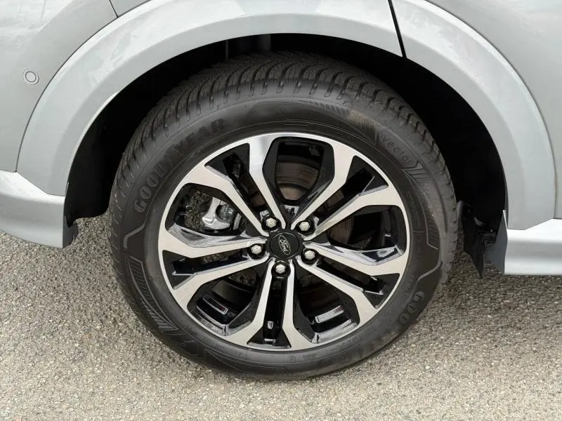 Gros plan sur la roue avant droite du Ford Puma 2024 gris, avec jante alliage bicolore et pneu Goodyear visible.