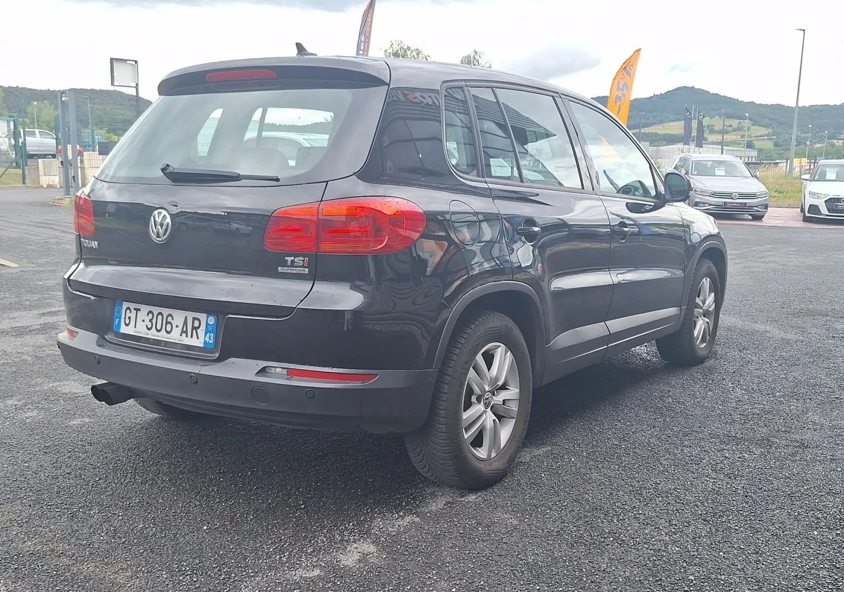 Volkswagen Tiguan noire vue 3/4 arrière droit, avec jantes alliage 16 pouces et feux arrière rouges visibles.