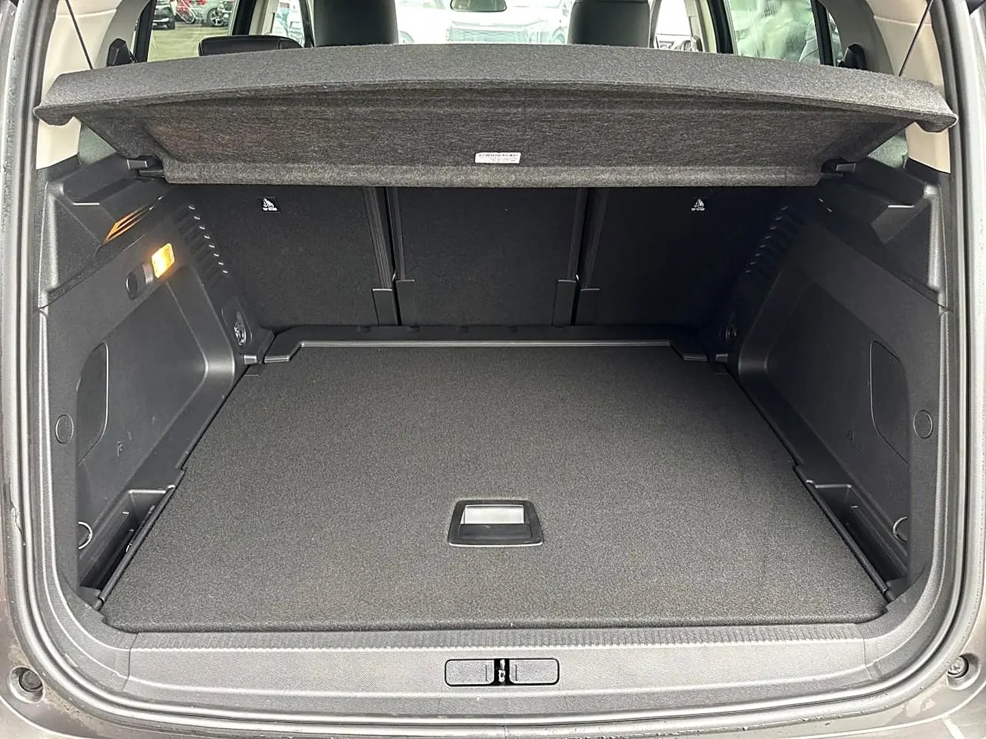 Coffre ouvert vu de l'arrière du Citroën C5 Aircross gris platinium, avec cache-bagages déployé et intérieur noir.