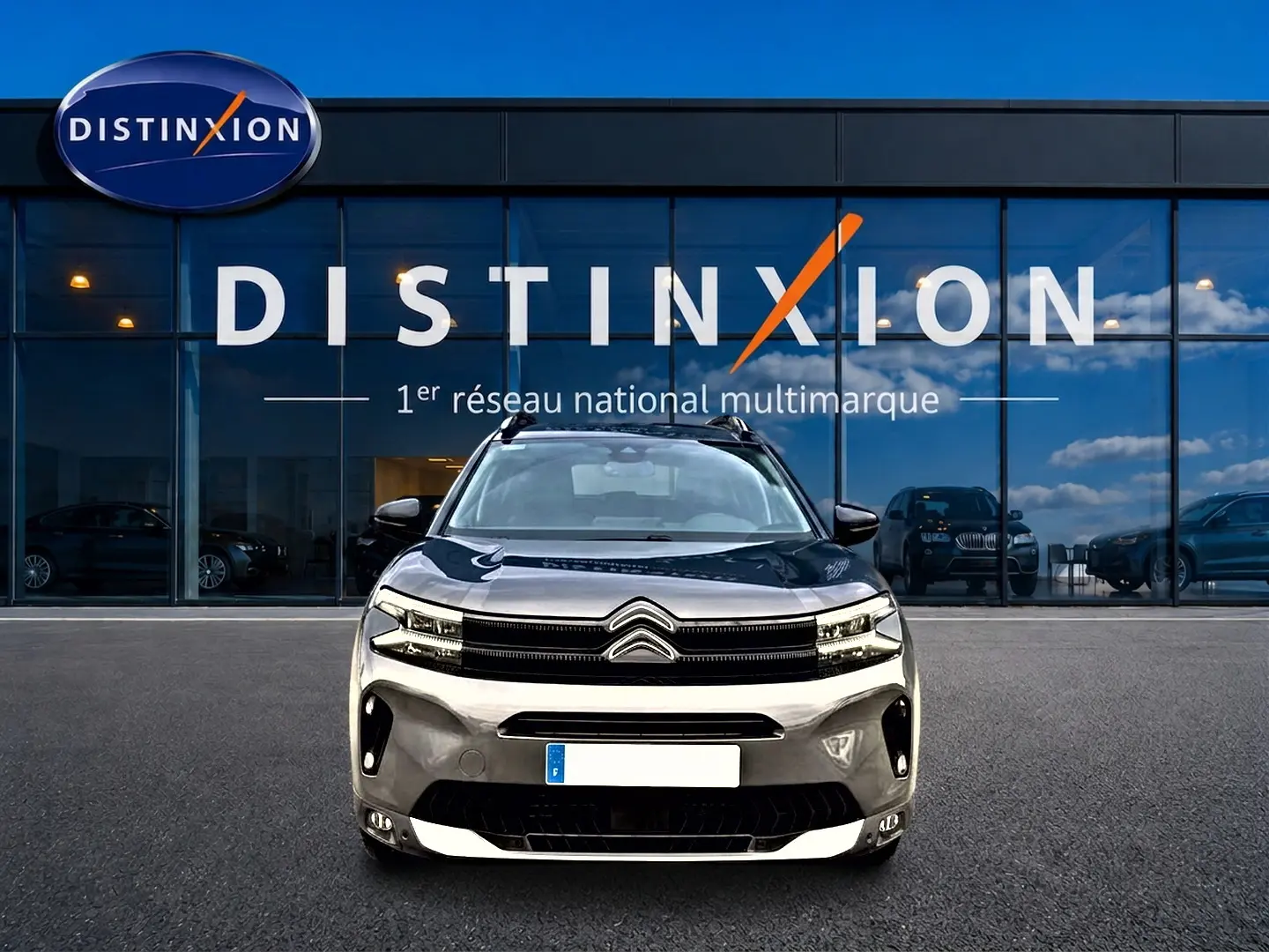Vue avant d'un Citroën C5 Aircross gris platinium avec calandre noire et barres de toit visibles.