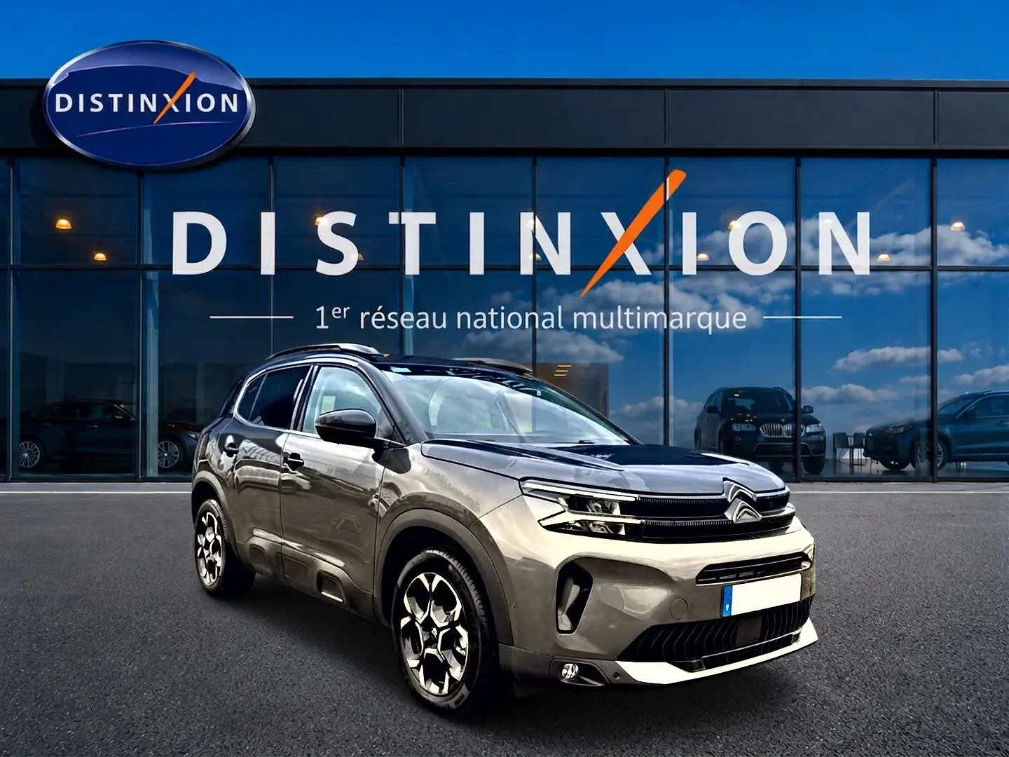 Citroën C5 Aircross gris platinium vue 3/4 avant droit avec jantes alu et barres de toit devant showroom Distinxion.