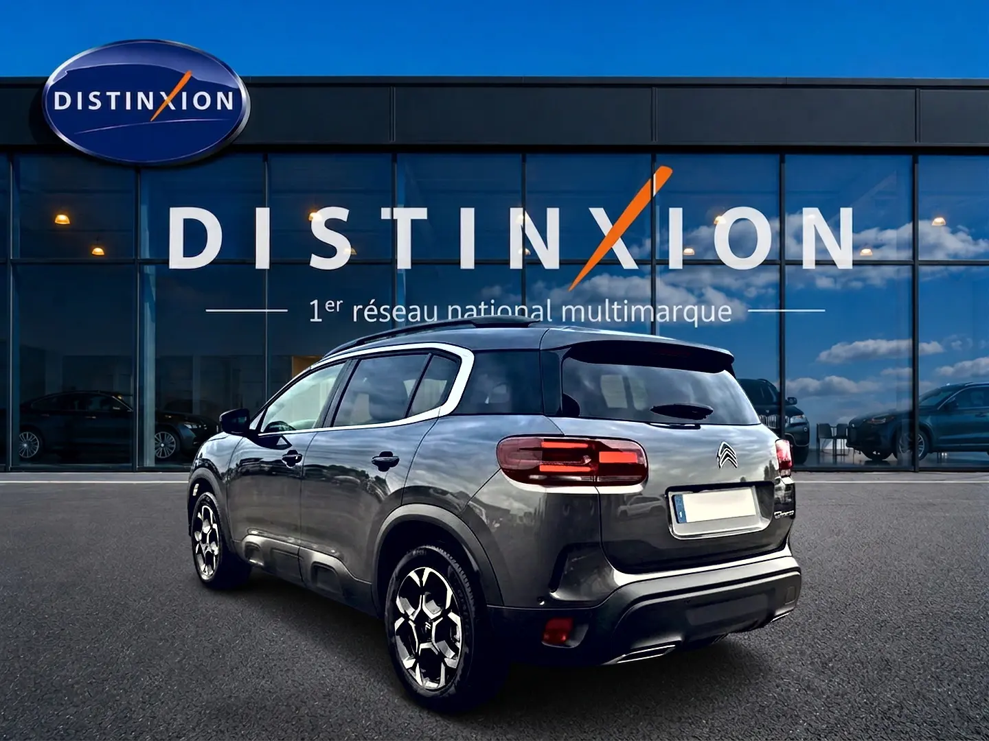 Citroën C5 Aircross gris platinium vue 3/4 arrière droit, avec jantes alu et barres de toit visibles.