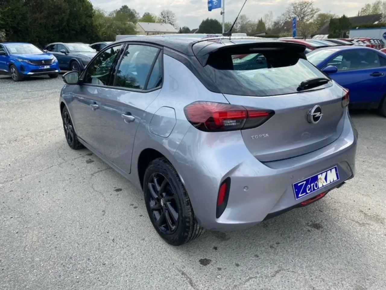 Opel Corsa gris magnetic vue 3/4 arrière droit, toit noir, jantes alliage noires et feux arrière LED visibles.