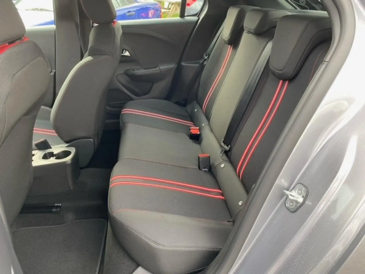 Vue côté droit de l'habitacle arrière de l'Opel Corsa 2022, sellerie tissu noire avec bandes rouges contrastantes.