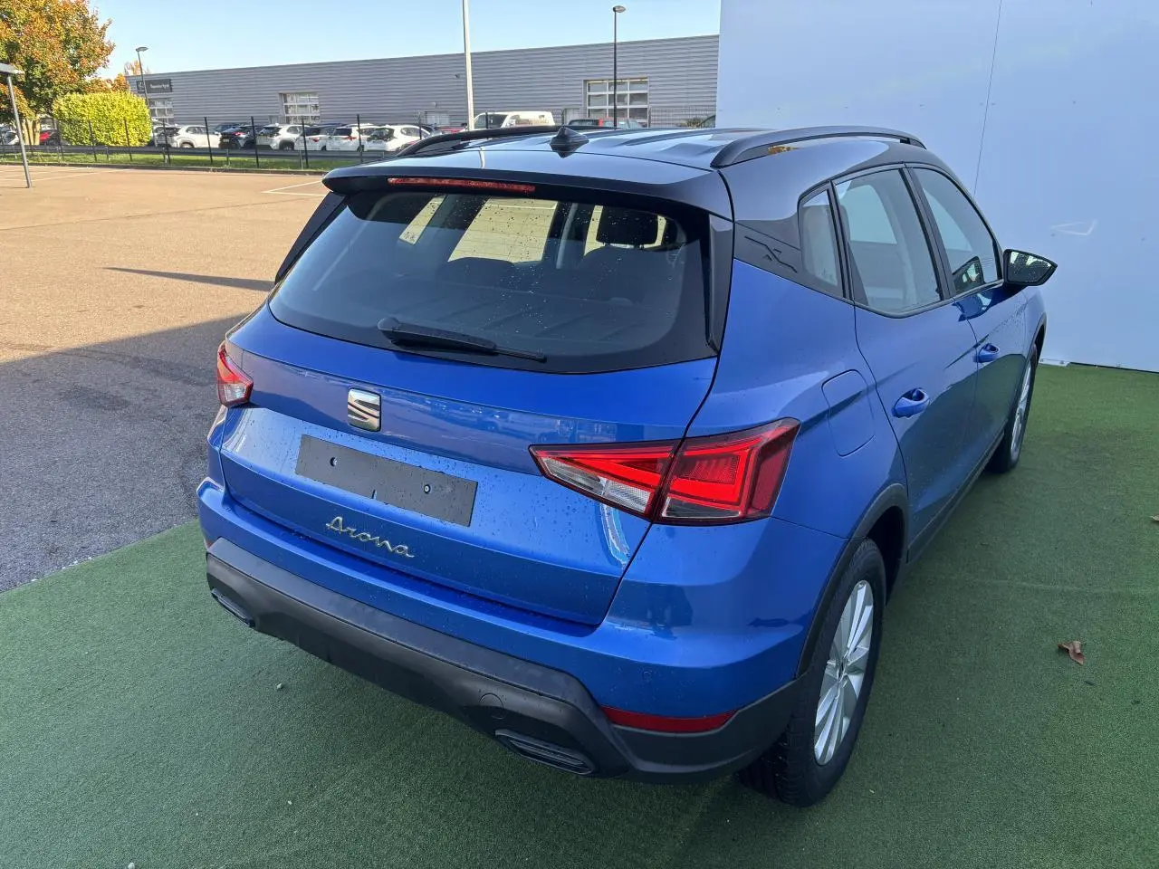 Vue 3/4 arrière droite d'un SEAT Arona bleu saphir avec toit noir, jantes alliage et feux arrière LED distinctifs.