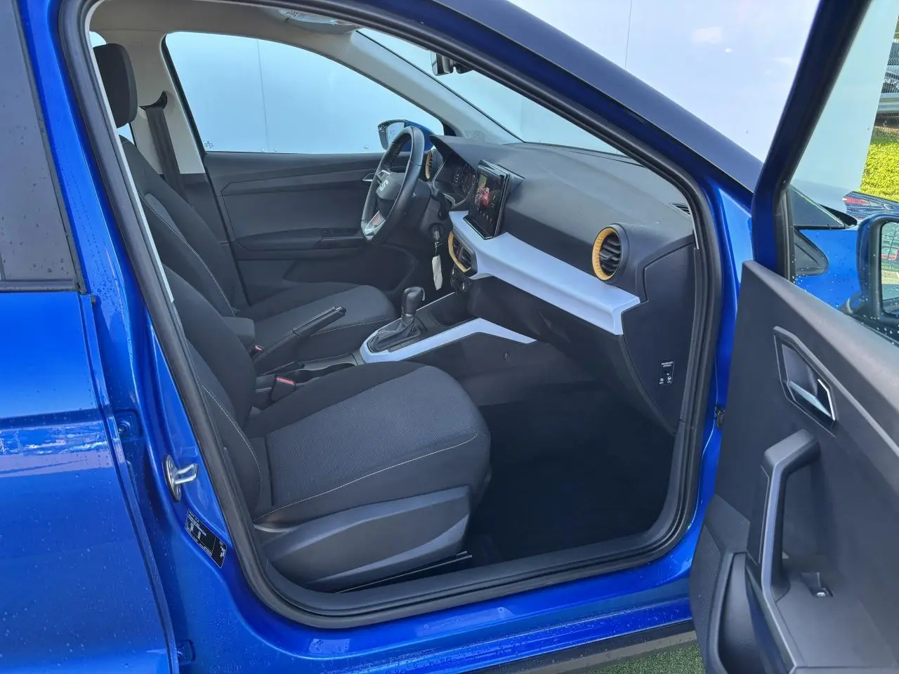 Vue intérieure côté conducteur de la SEAT Arona bleu saphir avec tableau de bord noir et inserts blancs.