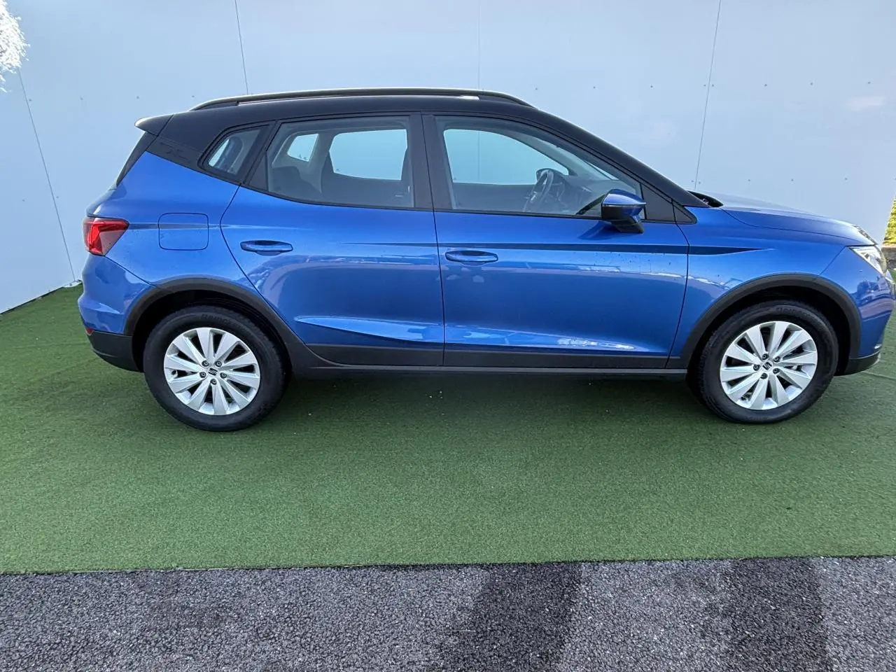 Vue de profil côté gauche d'un SEAT Arona 2024 bleu saphir avec toit noir et jantes alliage 16 pouces.