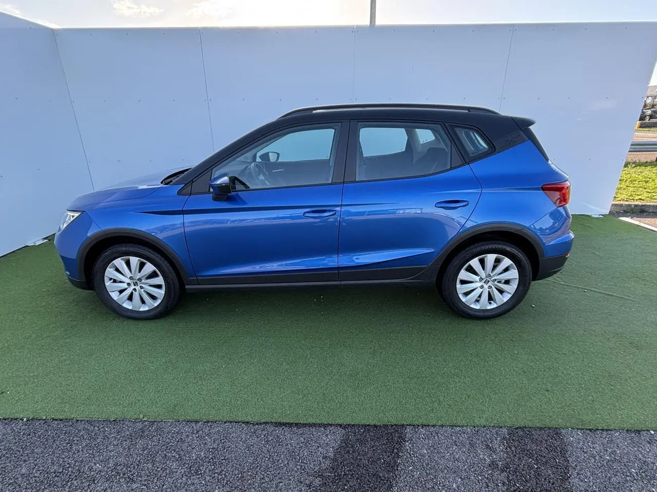 Vue de profil côté gauche d'une SEAT Arona 2024 bleu saphir avec toit noir et jantes alliage 16 pouces.