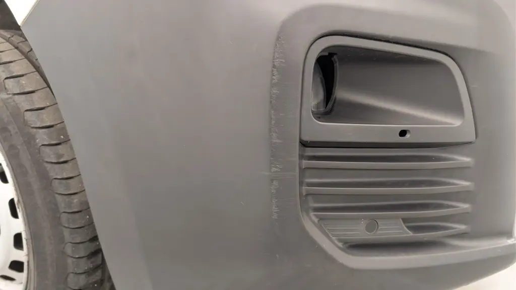 Gros plan sur la prise d'air noire côté gauche du pare-chocs avant du Citroën Berlingo Van blanc Banquise.