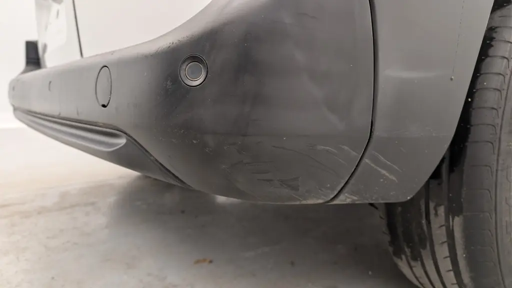 Gros plan sur le pare-chocs arrière droit noir du Citroën Berlingo Van blanc, montrant le capteur de recul et la roue.