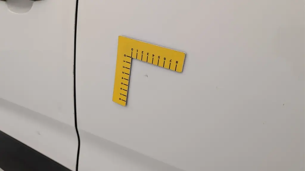 Détail de la porte latérale droite blanche Banquise du Citroën Berlingo Fourgon 2020 avec petite éraflure mesurée par un gabarit jaune.