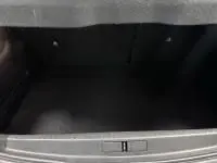 Coffre ouvert d'une Peugeot 208 1.2 PureTech 100 Style gris 2021, montrant l'espace de rangement vide et l'habillage intérieur.
