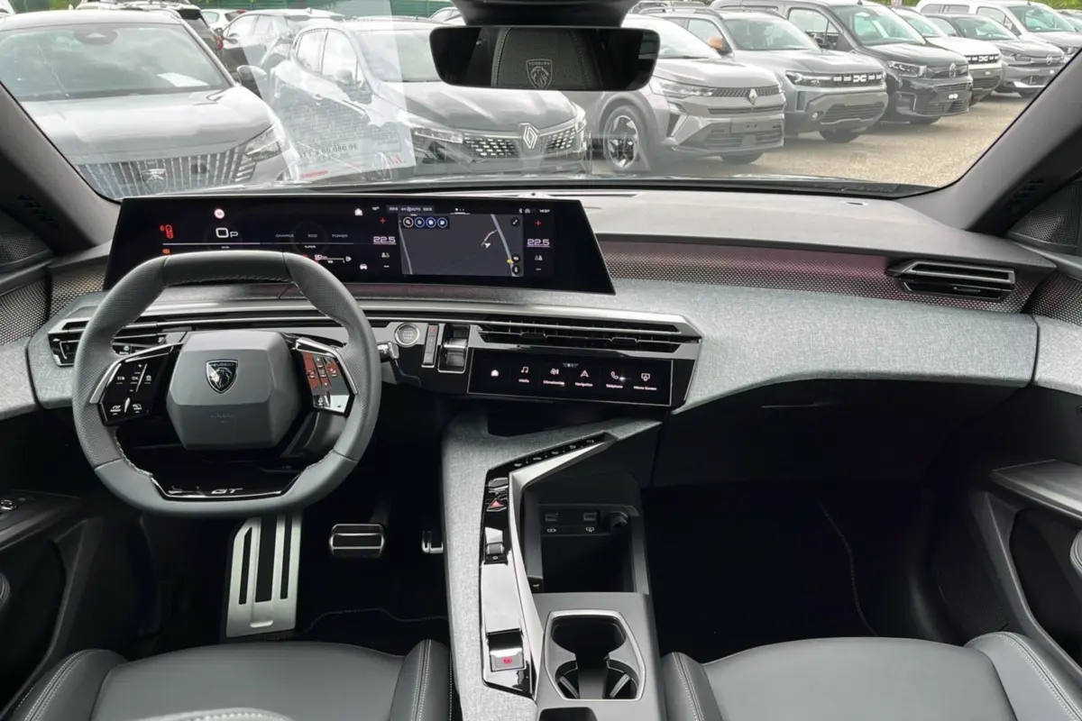 Vue intérieure avant du Peugeot 5008 Hybrid 145 GT 2025, tableau de bord moderne avec écran large et volant cuir multifonctions.