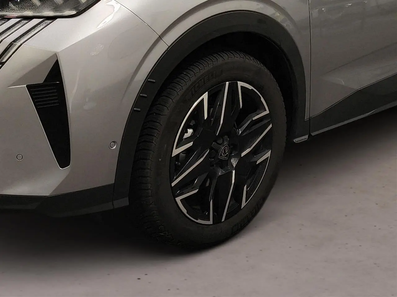 Gros plan sur la roue avant gauche et partie du pare-chocs gris Artense du Peugeot 3008 Hybrid 145 e-DSC6 GT.