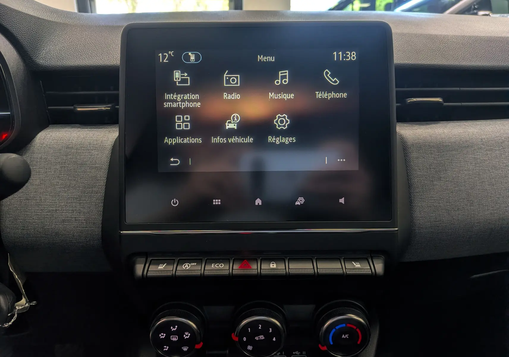 Écran tactile central de la Renault Clio V gris schiste, affichant le menu multimédia avec commandes climatisation en dessous.