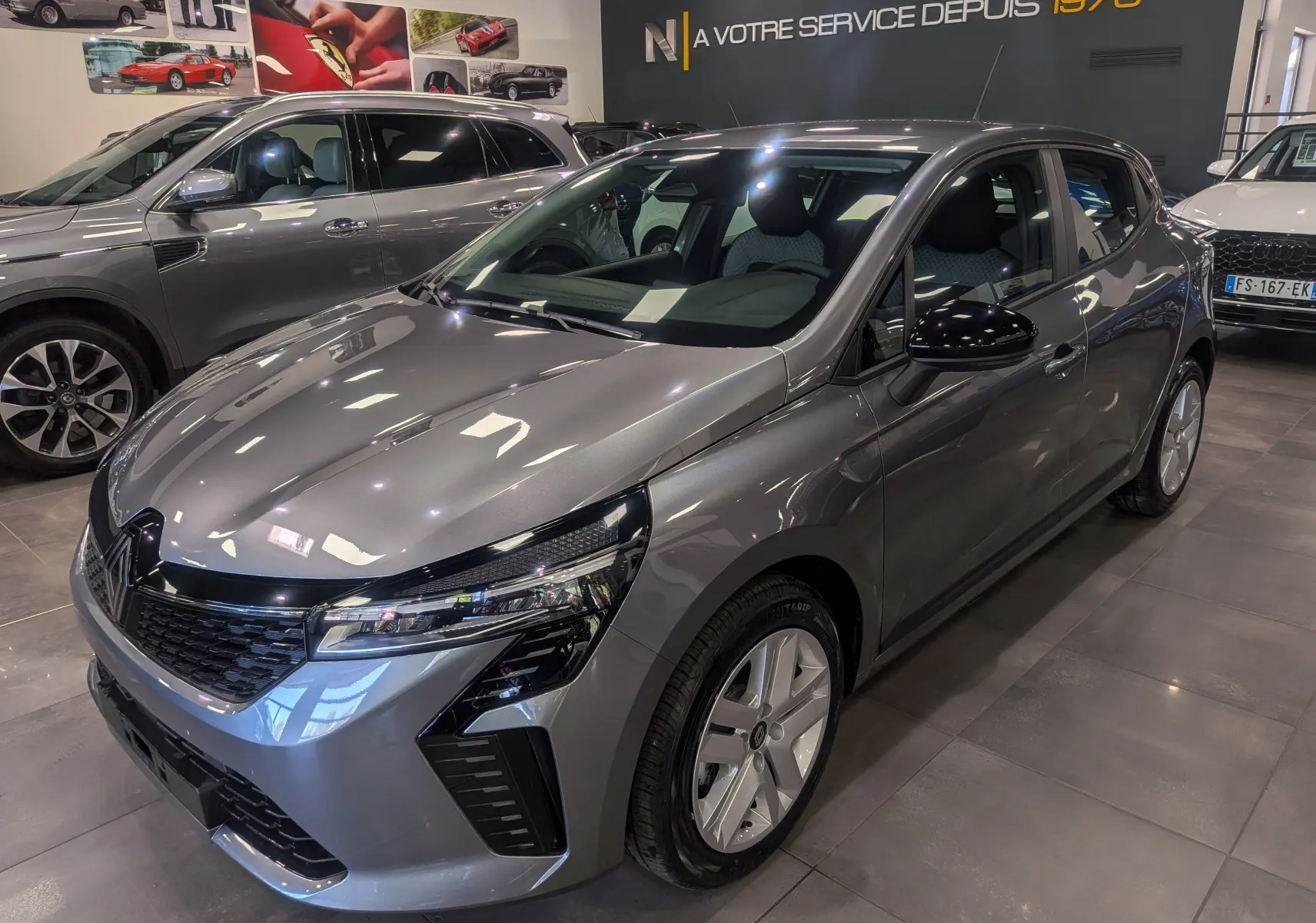 Renault Clio V Blue dCi 100 en gris schiste, vue 3/4 avant droit, avec calandre noire et jantes spécifiques.