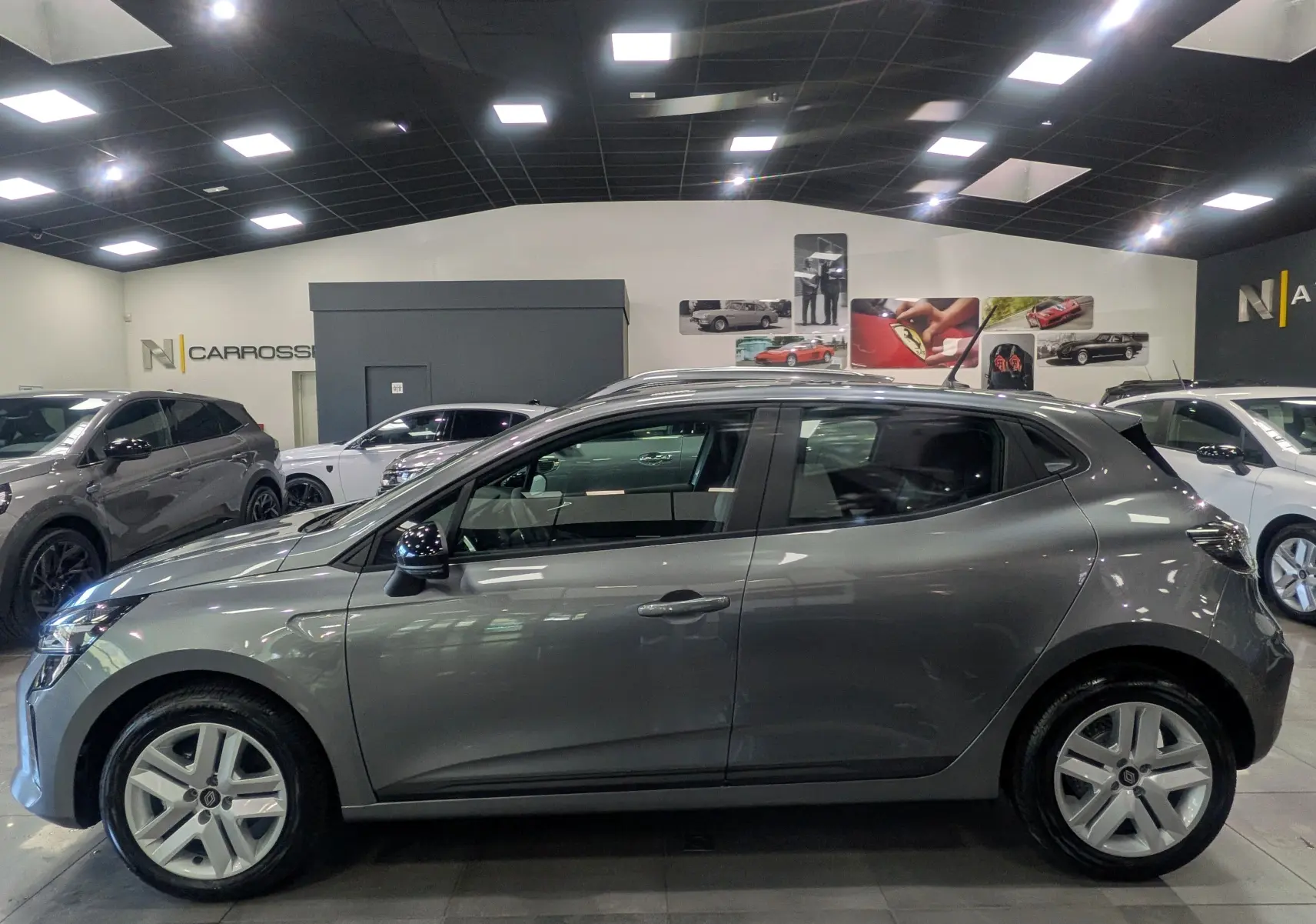 Profil côté gauche d'une Renault Clio V gris schiste 2025 en intérieur, avec jantes alliage et lignes épurées.