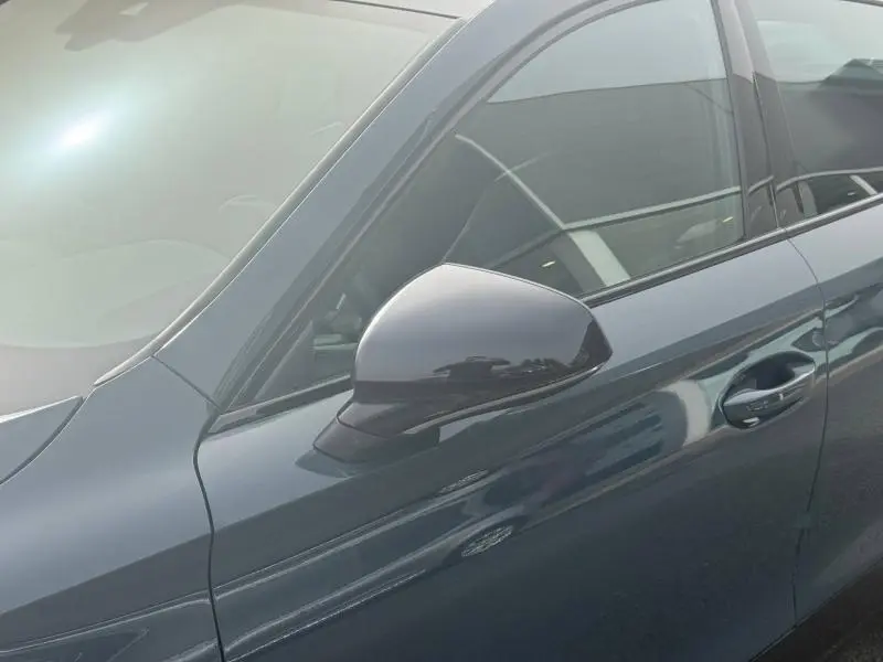 Gros plan sur le rétroviseur côté gauche d’un CUPRA Formentor bleu Fjord avec poignée de porte assortie.