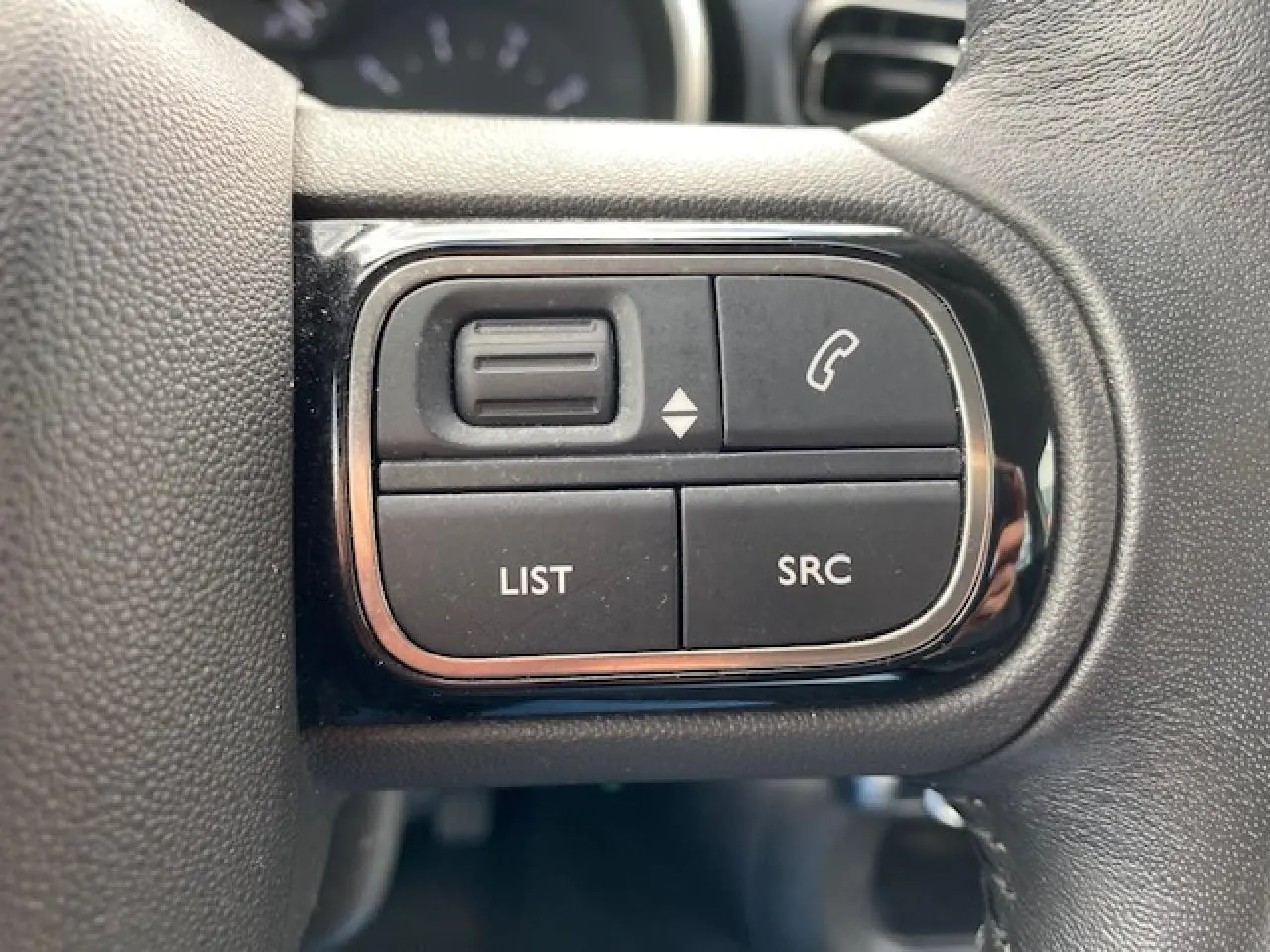 Gros plan sur les commandes au volant noir de la Citroën C3 gris clair, boutons d'appel et navigation audio visibles.