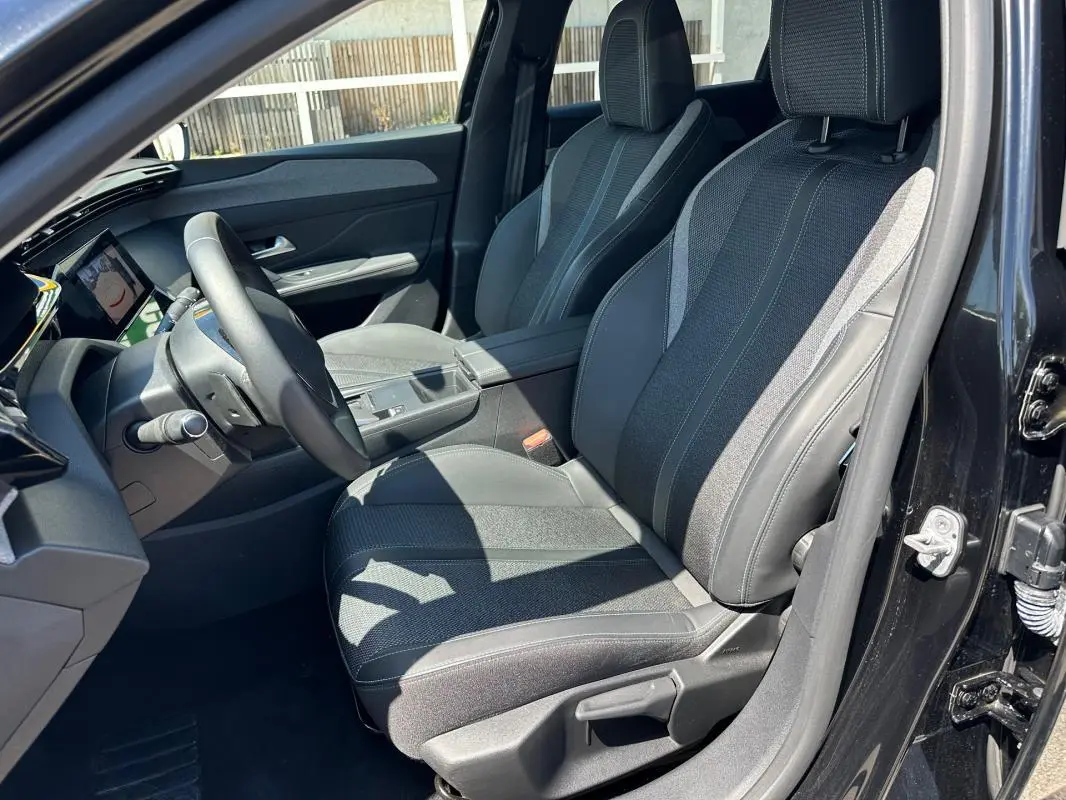 Intérieur avant droit du Peugeot 308 SW Hybrid 145 noir, montrant les sièges en tissu et cuir avec détails contrastants.