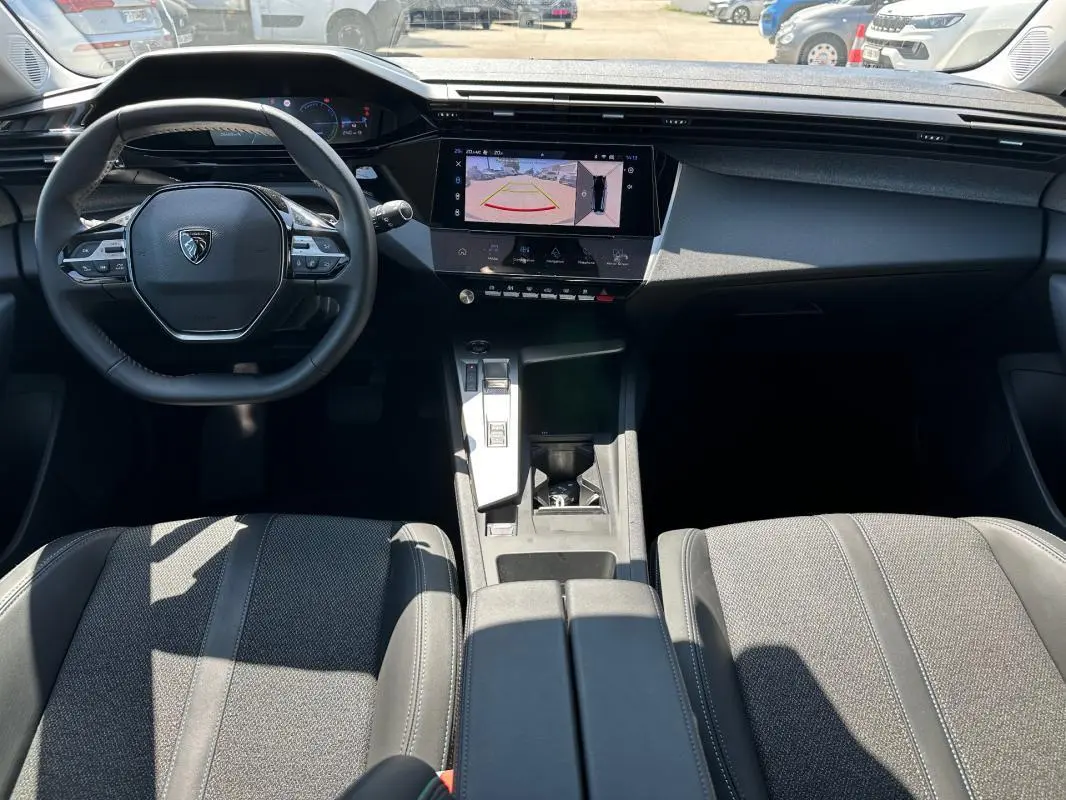 Vue intérieure avant du Peugeot 308 SW Hybrid 145 e-DCS6 Allure 2025, avec tableau de bord numérique et écran tactile central.