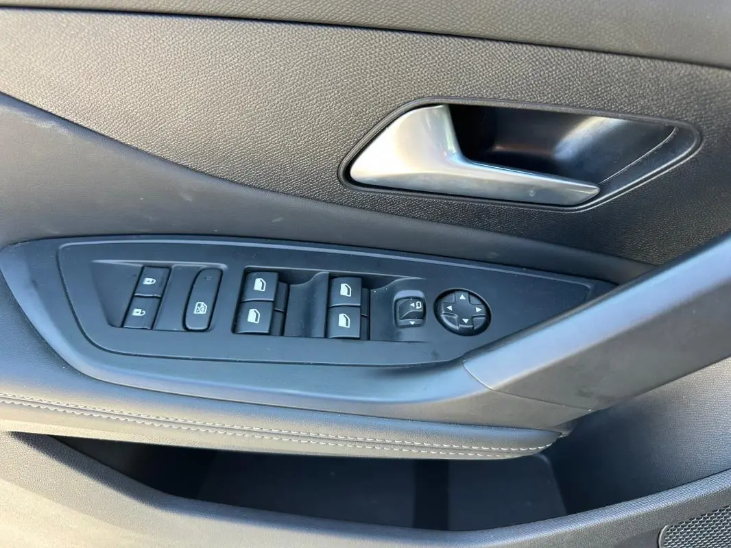 Gros plan sur la commande des vitres et rétroviseurs côté conducteur du Peugeot 308 SW Hybrid noir, finition Allure 2025.