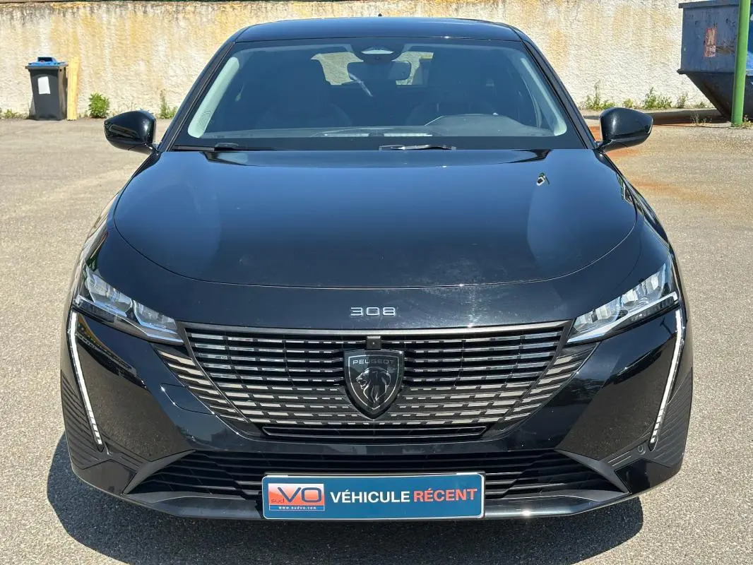 Vue frontale d'une Peugeot 308 SW Hybrid noire 2025 avec calandre distinctive et logo Peugeot central.