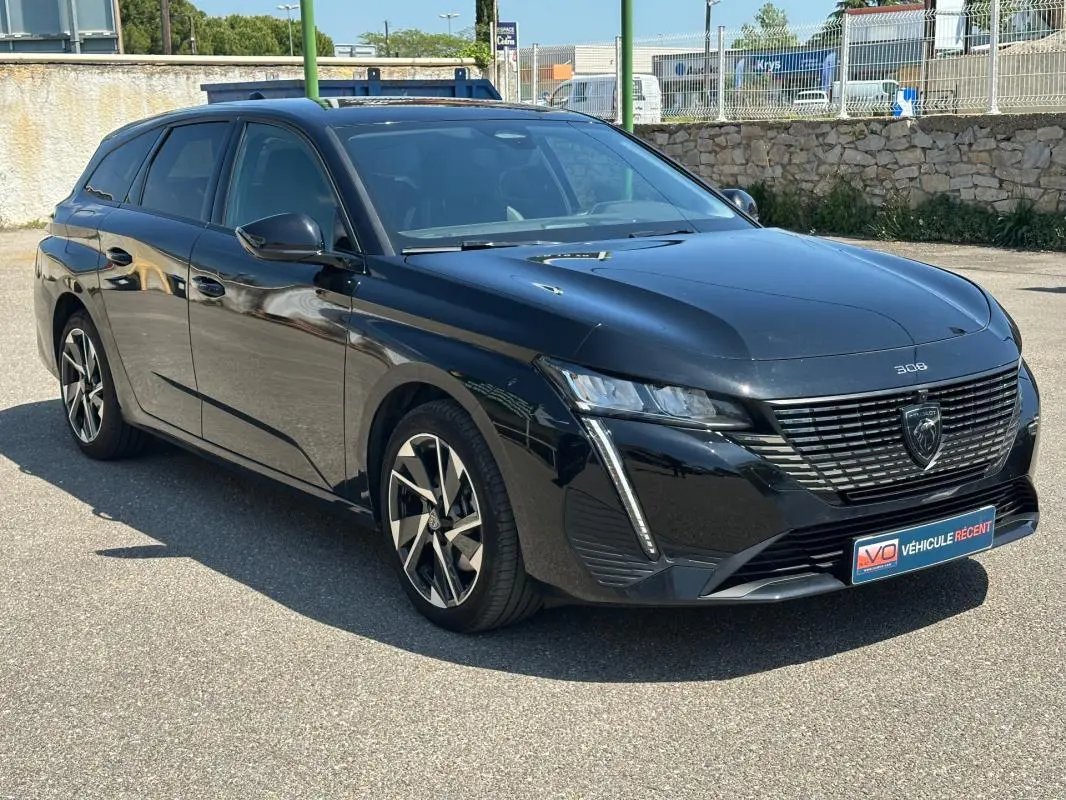 Peugeot 308 SW Hybrid 145 Allure noir vue 3/4 avant droit, avec calandre distinctive et feux LED verticaux.