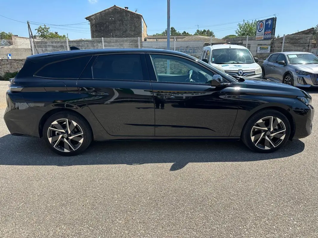 Peugeot 308 SW Hybrid 145 e-DCS6 Allure noir vue de profil côté gauche, stationnée en extérieur au soleil.