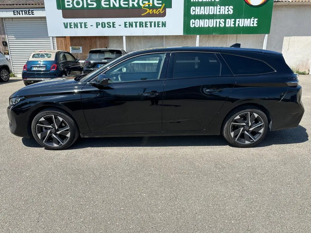 Profil côté gauche d'une Peugeot 308 SW Hybrid 145 e-DCS6 Allure noire, finition 2025 avec jantes alliage distinctives.