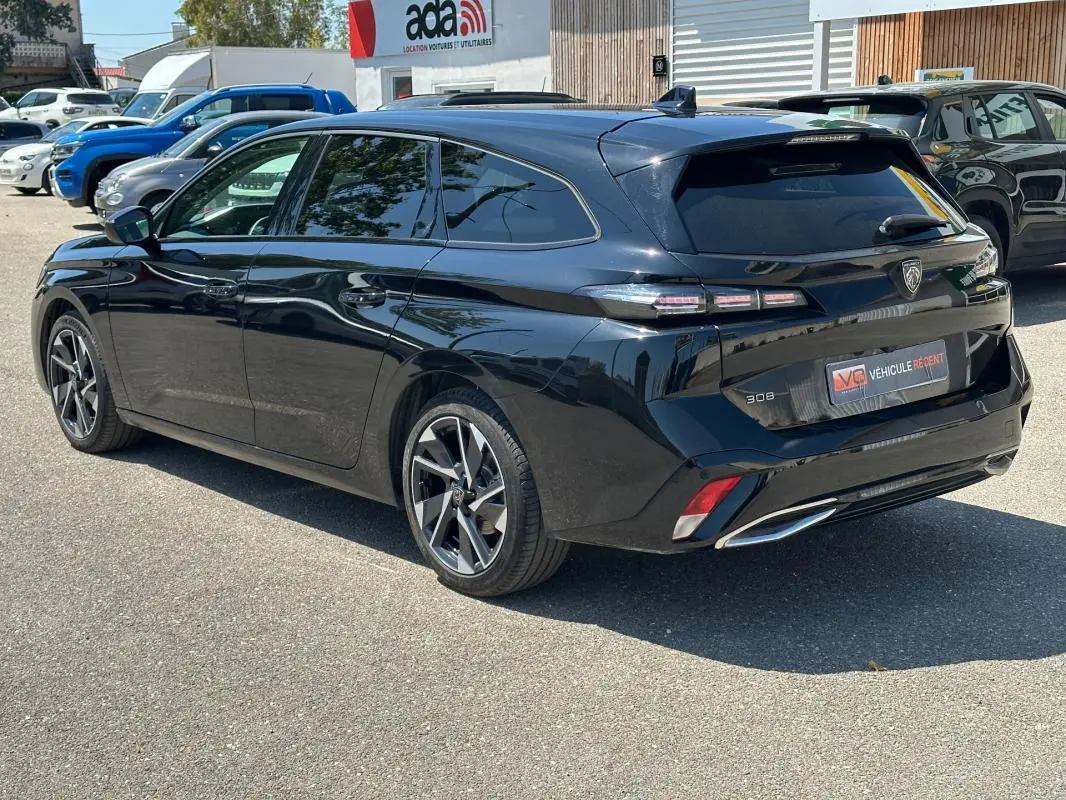 Peugeot 308 SW Hybrid noir vue 3/4 arrière droit, avec feux arrière distinctifs et jantes alliage modernes.