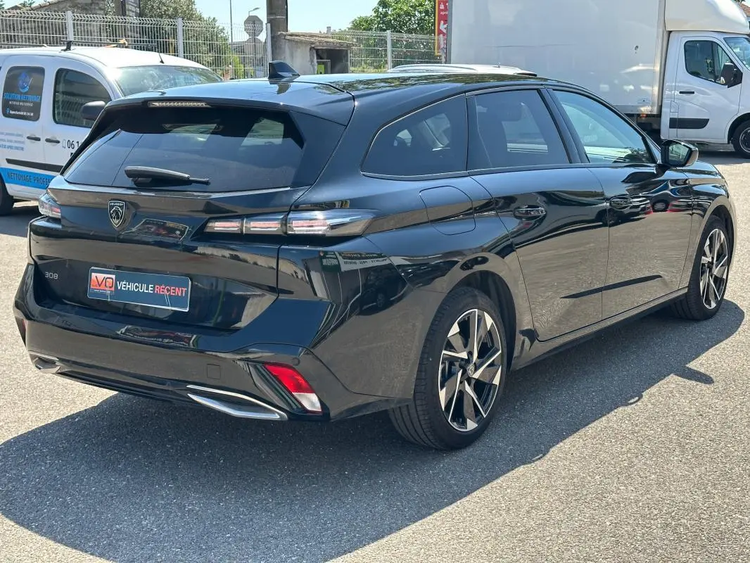 Peugeot 308 SW Hybrid noir vue 3/4 arrière droit, avec feux arrière LED et jantes alliage distinctives.