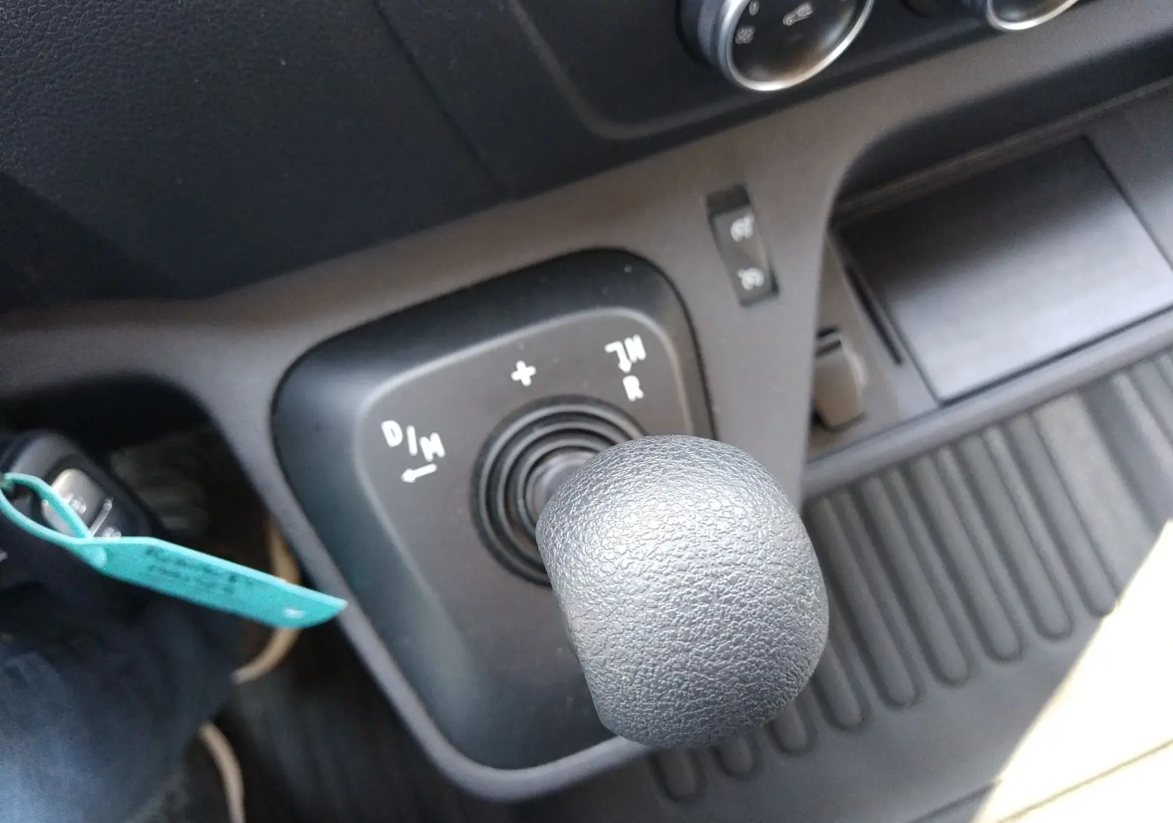 Gros plan sur le levier de vitesses automatique noir du Renault Master III blanc, avec commandes de boîte et console environnante.
