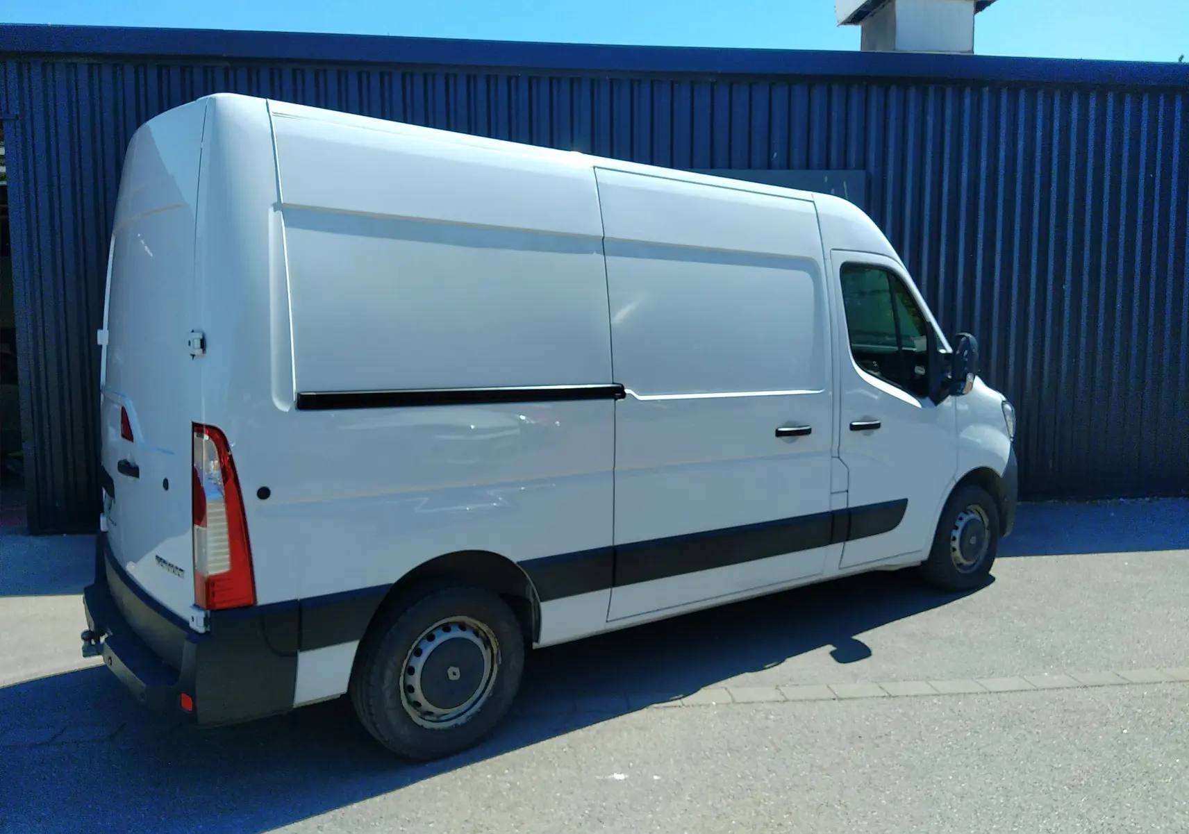 Renault Master blanc vu en 3/4 arrière droit, fourgon utilitaire avec porte latérale coulissante et attelage.