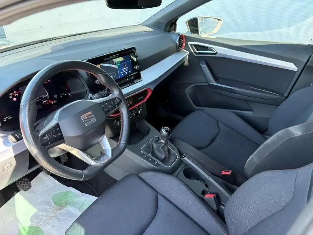 Vue intérieure côté conducteur de la SEAT Ibiza 1.0 TSI 95 FR 2025, volant cuir, écran tactile et sellerie noire.