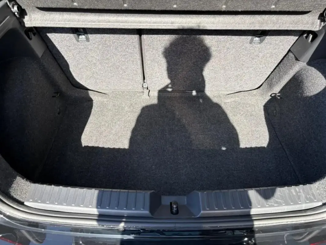 Vue plongeante sur le coffre vide gris foncé d'une SEAT IBIZA 2025 noire, avec banquette arrière rabattue.