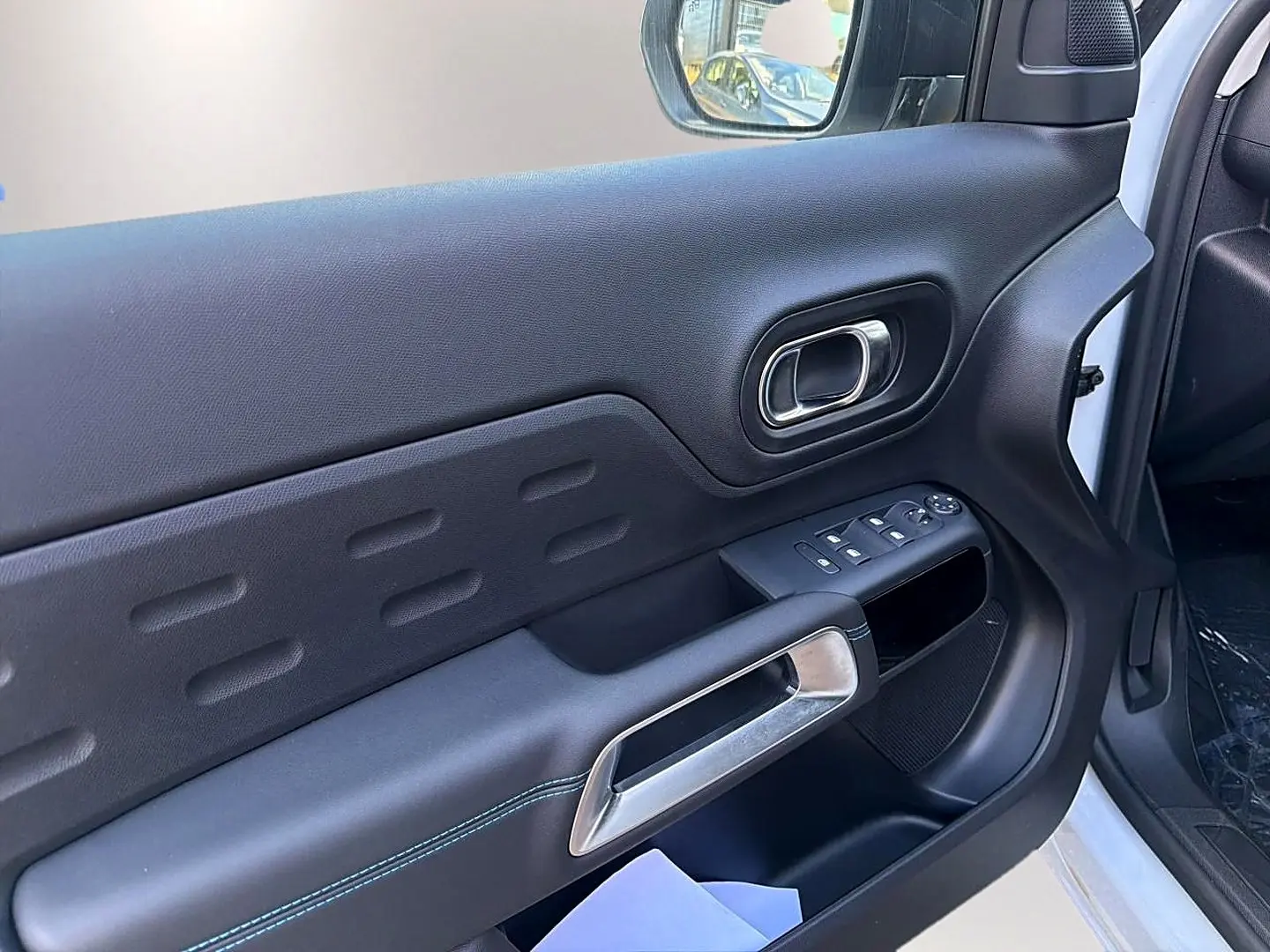 Vue intérieure côté conducteur de la porte noire du Citroën C5 Aircross blanc avec commandes des vitres et poignée argentée.