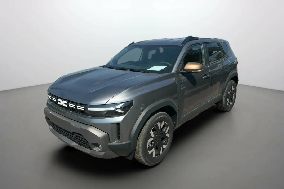 Dacia Duster HEV 140 gris schiste vu en 3/4 avant droit avec rétroviseur bronze et jantes noires distinctives.