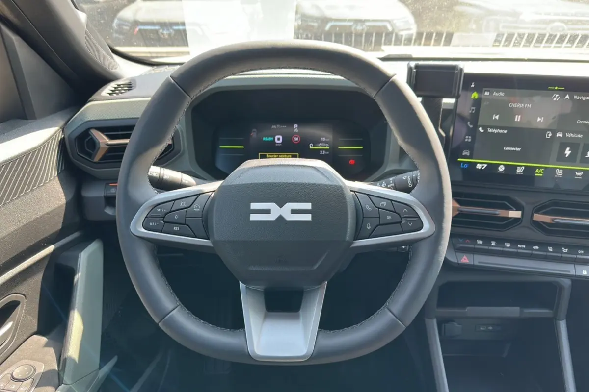 Vue intérieure centrée sur le volant du Dacia Duster HEV 140 Extreme Pack Hiver 2025 avec tableau de bord numérique.