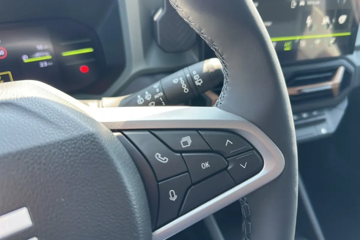 Gros plan sur les commandes au volant du Dacia Duster HEV 140 Extreme Pack Hiver 2025, intérieur noir moderne.
