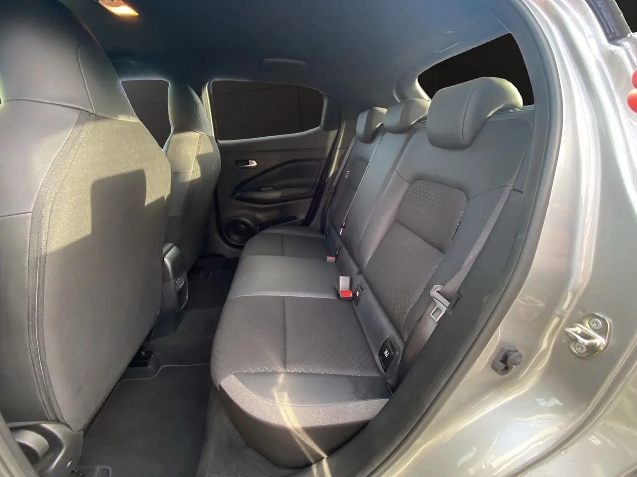 Vue intérieure côté droit sur la banquette arrière noire en tissu du Nissan Juke 2025 gris perle avec toit noir.